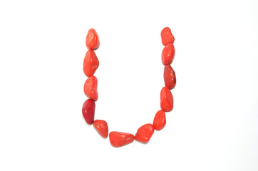 Alphabet in red pebbles on white background
