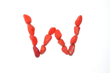 Alphabet in red pebbles on white background