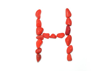 Alphabet in red pebbles on white background