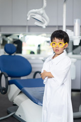 Fototapeta na wymiar Little Asian doctor dentist boy with a dentist suit, standing in the dentist clinic.