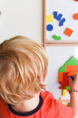 Child playing with colourful puzzle toy making shapes to learn at home