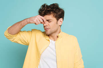 Man with closed eyes suffering from runny nose isolated on blue