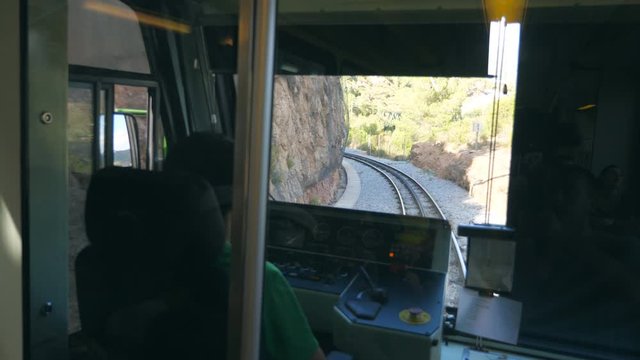 Unrecognizable train driver drives electrical train among mountain road. Point of view from driver cabin to railway tracks. Rear back view POV Slow motion Close up
