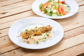 chicken kebab with rice and salad on the wooden background