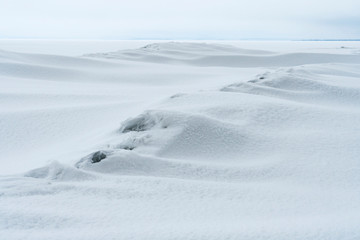 Fototapeta na wymiar The smooth lines of snow drifts with a granular structure