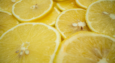 Many slices of freshly cut lemon lie on top of each other. Close up shot