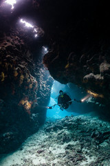 typical underwater cave in a red sea reef with an underwater photographer diver