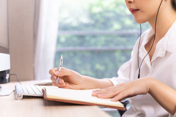Young Asian woman taking online lesson, e-learning on computer while self-isolation work at home