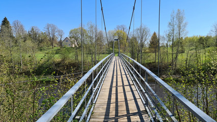 Suspension bridge over the Salaca river in Latvia in the national park in spring on a sunny day
