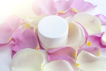 Natural organic homemade cosmetics concept. Skin care (therapy), beauty products: containers with cream among delicate rose flowers petals on white background. Close up mock up