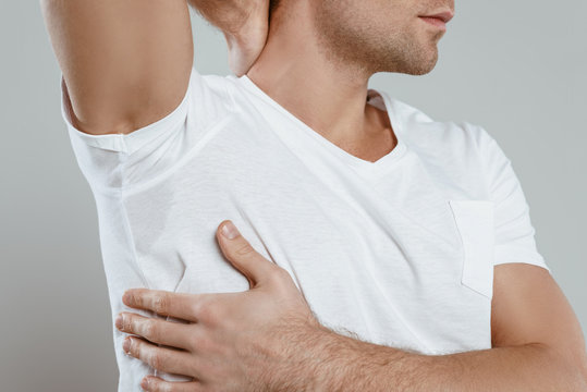 Cropped view of man showing sweaty armpit isolated on grey