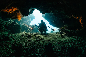 typical underwater cave in a red sea reef with an underwater photographer diver