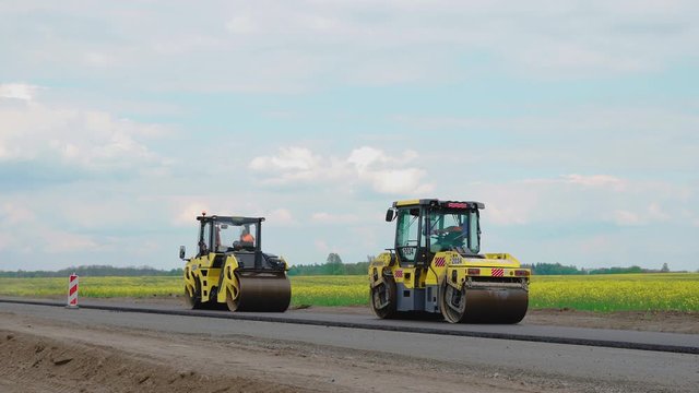Roller machines make new asphalt roads. The asphalt paver squeezes hot asphalt.