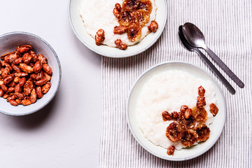 Creamy Rice Porridge or Pudding with caramelized bananas and nuts in bowls on grey concrete background. Selective focus