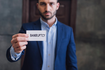 Selective focus of collector showing card with bankruptcy lettering and looking at camera