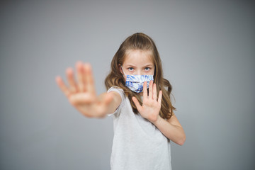 beautiful young girl with self-made mouth nose mask in front of grey background during corona