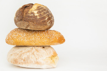 Pile of three wheat and rye breads with cereals. Fresh delicious loafs and pastry isolated on white background. Studio shot. Side view. Homemade bakery and nutrition concept