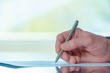 Man signs a document form with a ballpoint pen in the office