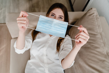 woman at home on couch wearing mask taking her on and off