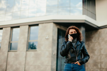 young woman with mobile phone in the city in mask. coronavirus. covid-19.  