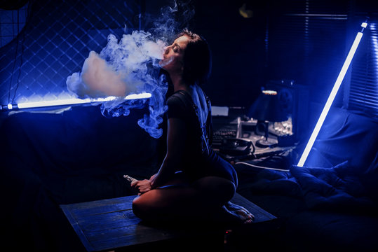 Sexy woman with vaping device, smoke e-liquid instead of nicotine cigarettes. Tobacco free e-juice. Vaping concept. Modern girl smoking vape