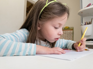 a little girl draws with colored pencils with her left hand, children's joint creativity