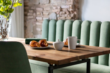 Breakfast with oranges, fruits, croissants, cake and coffee, magazine decorated table 