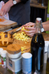 Man Grabbing a Handful of Diced Potatoes on Wooden Chopping Board