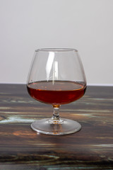 Glass with cognac on a wooden background. Dear elite alcohol.