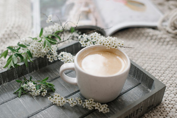 A cup of coffee on the wooden tray and knitting plaid