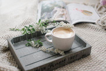 A cup of coffee on the wooden tray and knitting plaid