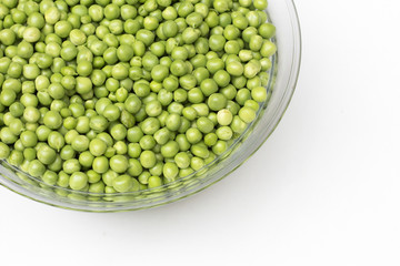 Fresh green peas in a glass bowl isolated on white background. top view