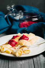 Pancakes with custard and raspberry sauce, dark wooden background, selective focus