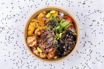 Poke bowl with chicken and vegetables on the white table.