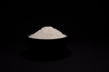 A bowl of sugar in a black copy space background. Food and product photography.