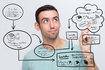 Closeup portrait of serious young handsome man looking and pointing at virtual hand drawn business flowcharts. Isolated front view on grey background.