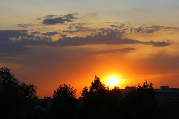 sunset on a yellow-orange sky with a purple cloud above the city