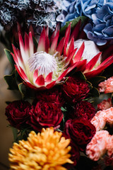 Beautiful blossoming nutan protea, roses, hydrangea, chrysanthemum flowers in orange, red, blue colors , fresh delivery at the florist shop