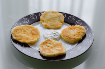 Cheese pancakes or syrniki (cheesecakes, curd fritters) with sour cream or smetana for breakfast