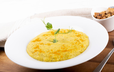 Mixed vegetable cream soup in a white bowl, isolated on a white background, on wooden cutting board