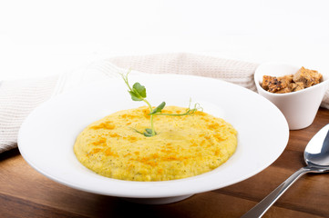 Mixed vegetable cream soup in a white bowl, isolated on a white background, on wooden cutting board
