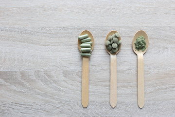 Herbal extract medicine tablets pills with capsules and powder or Fa thalai chon (Andrographis Paniculata), Acanthaceae in spoon on wooden background, Medical and healthcare concept