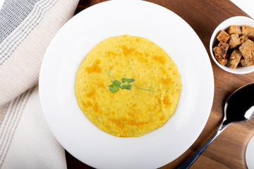Mixed vegetable cream soup in a white bowl, isolated on a white background, on wooden cutting board