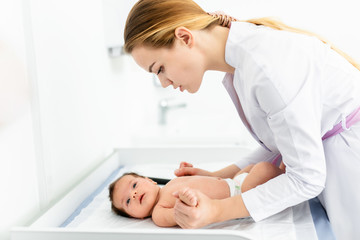 Obraz na płótnie Canvas medicine, healthcare and pediatrics concept - female pediatrician or neuropathist doctor or nurse checking baby patient's at clinic or hospital