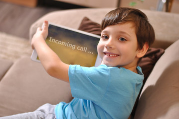 Online training education and communiction. Quarantine. Happy smiling kid boy holds incoming call tablet.