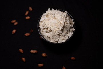 Top down image of a bowl of rice cereals decorated with scattered peanuts in a dark copy space background. Food and product photography.