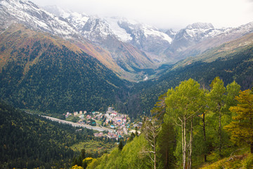 Fototapeta premium Dombay ski resort from the cableway chairelift, beautiful mountains landscape, small village and large snowy peaks in autumn, Caucasus, Russia