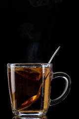 brewing tea from a tea bag in a transparent mug on a black background