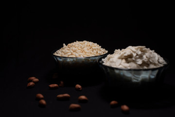 Two bowls full of puffed rice and rice cereals decorated with scattered peanuts in a dark copy space background. Food and product photography.