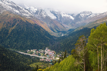 Naklejka premium Dombay ski resort from the Mount Mussa Achitara, beautiful mountains landscape, small village and snowy peaks, Caucasus, Russia